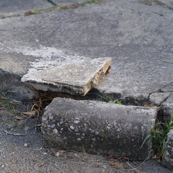 Cracked and uneven sidewalk slab forming a trip hazard