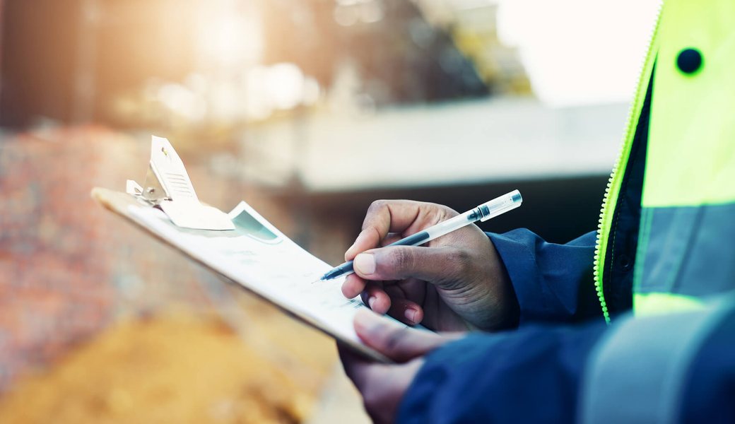 Hands recording inspection findings on a clipboard